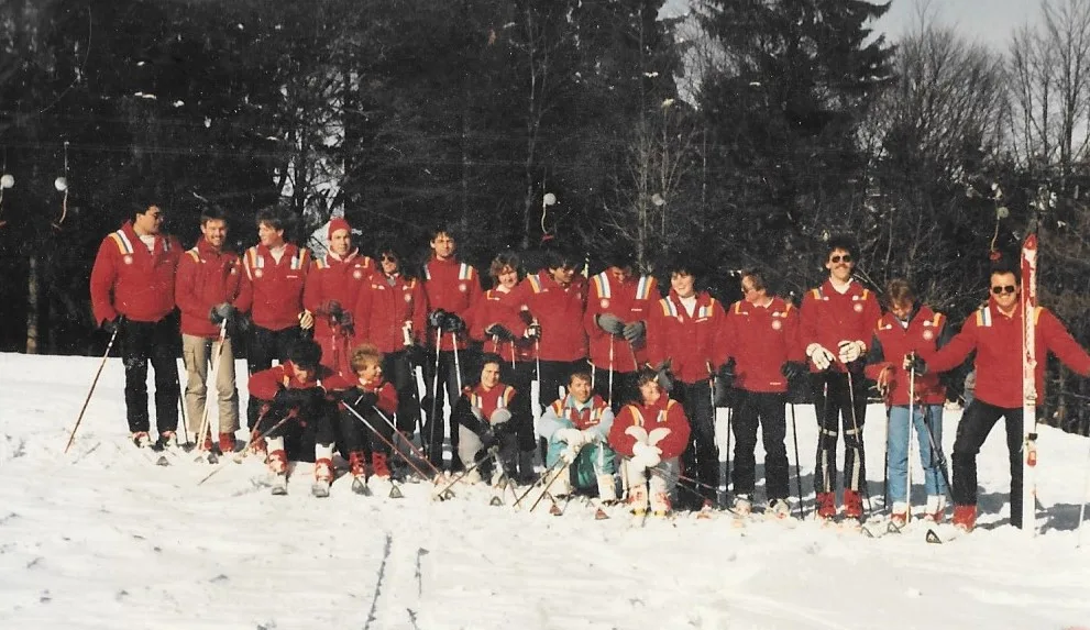 Eine Gruppe von Skilehrern steht und sitzt auf einem Hang mit Schnee.